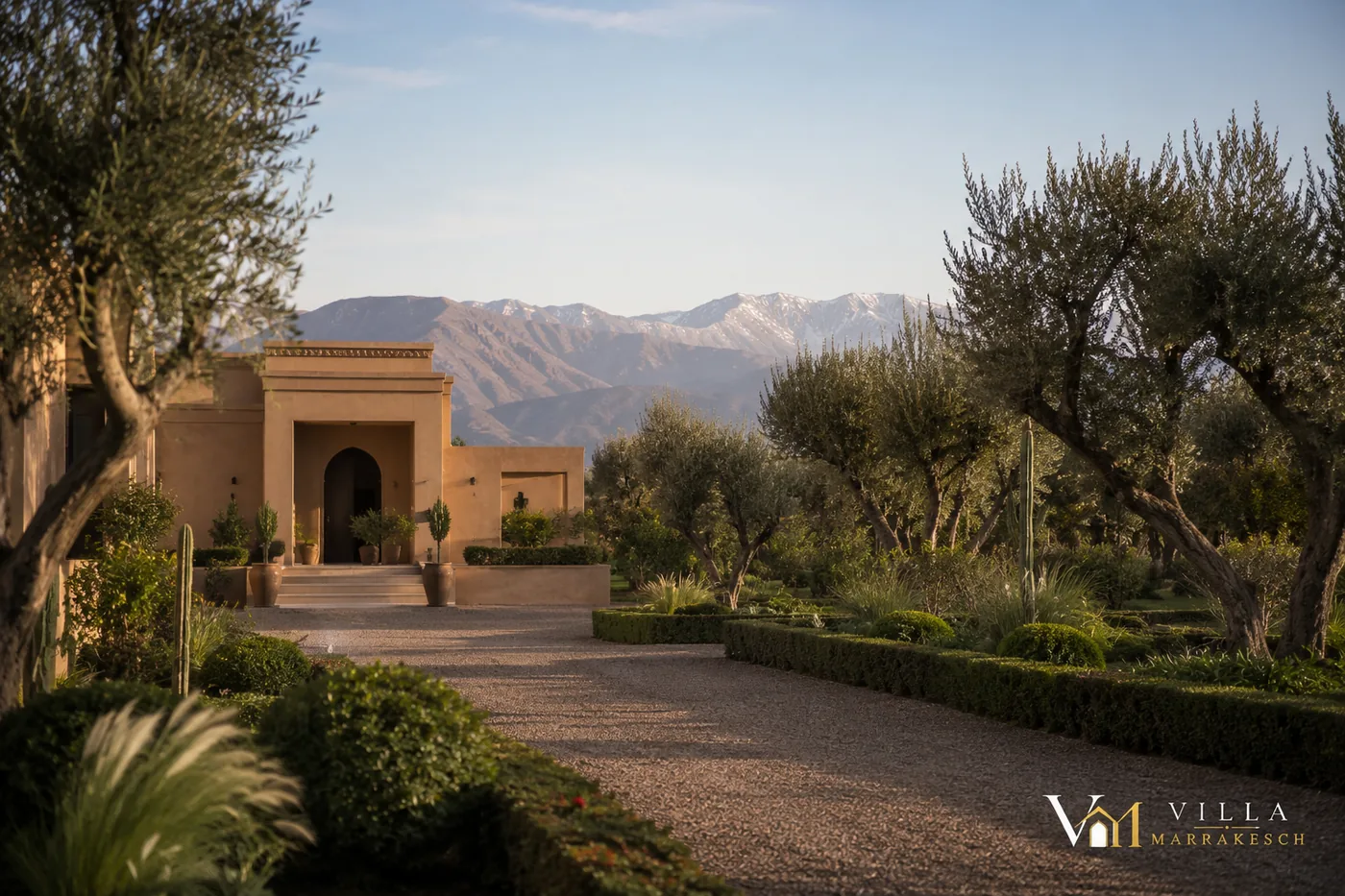 Zufahrt zu einer privaten Villa mit Olivenbäumen, Garten und Bergen im Hintergrund.